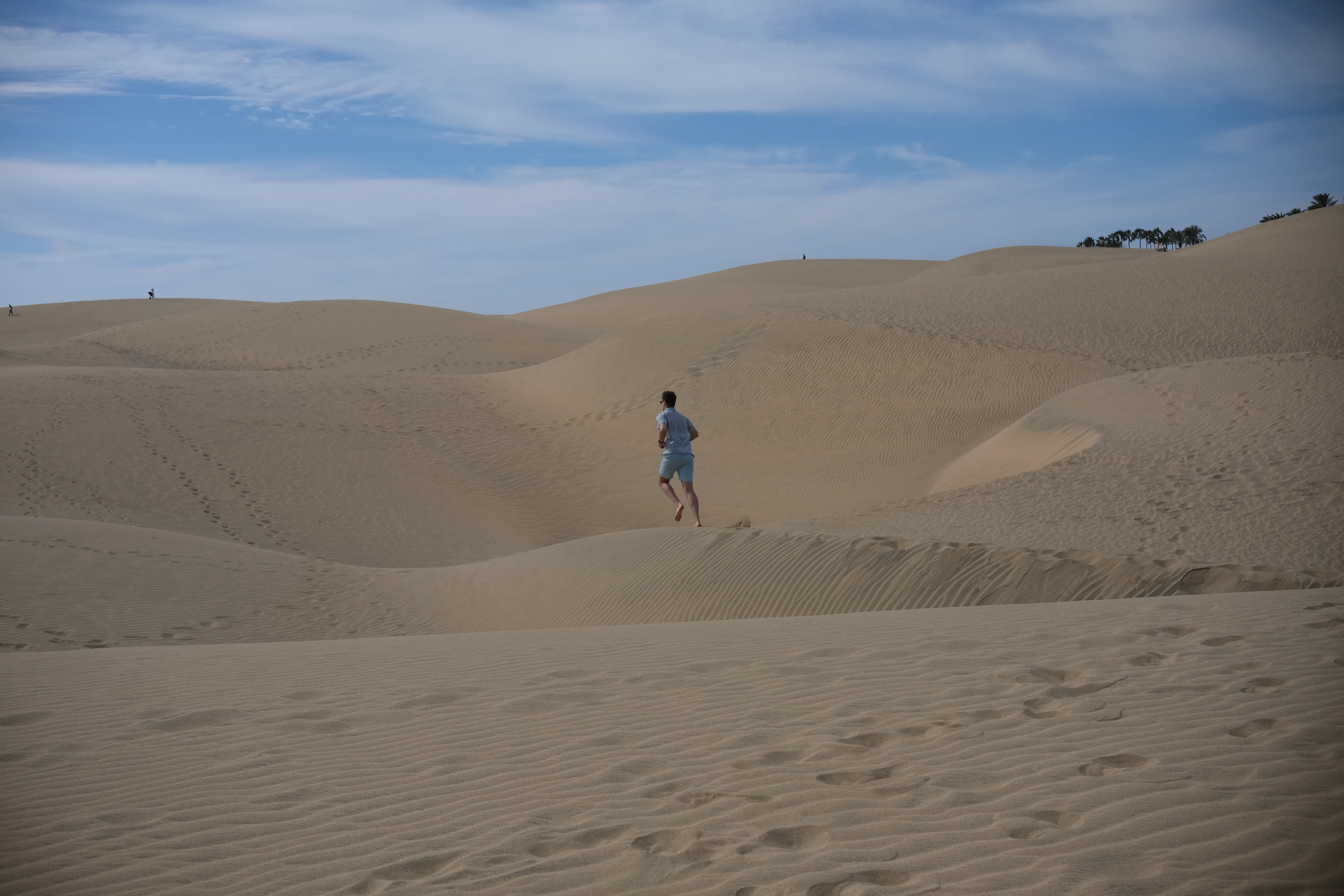 Connor runs along the ridge of a sand dune surrounded by other dunes.