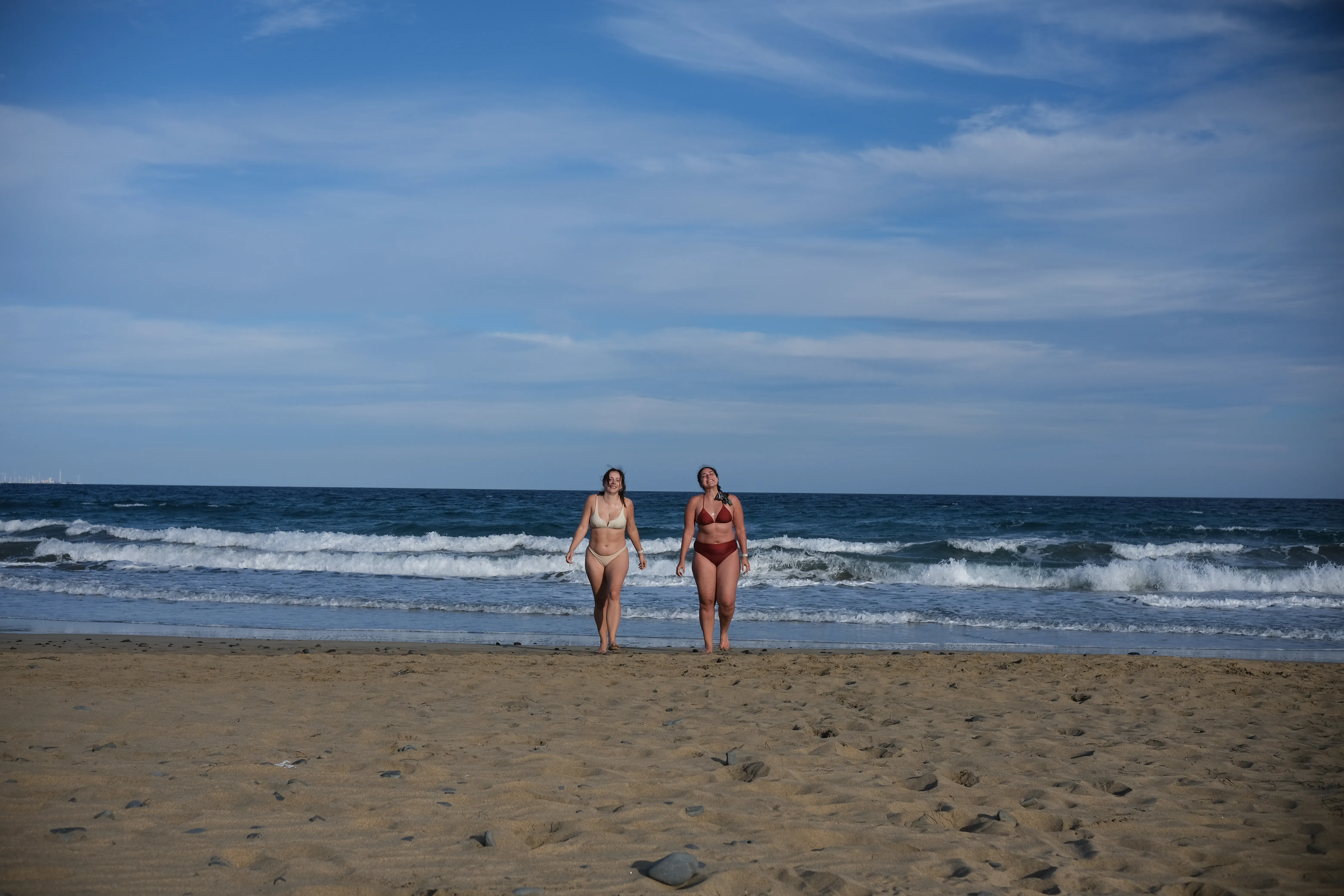 Ena and Alessandra walk back from a dip in the deep blue ocean waves.